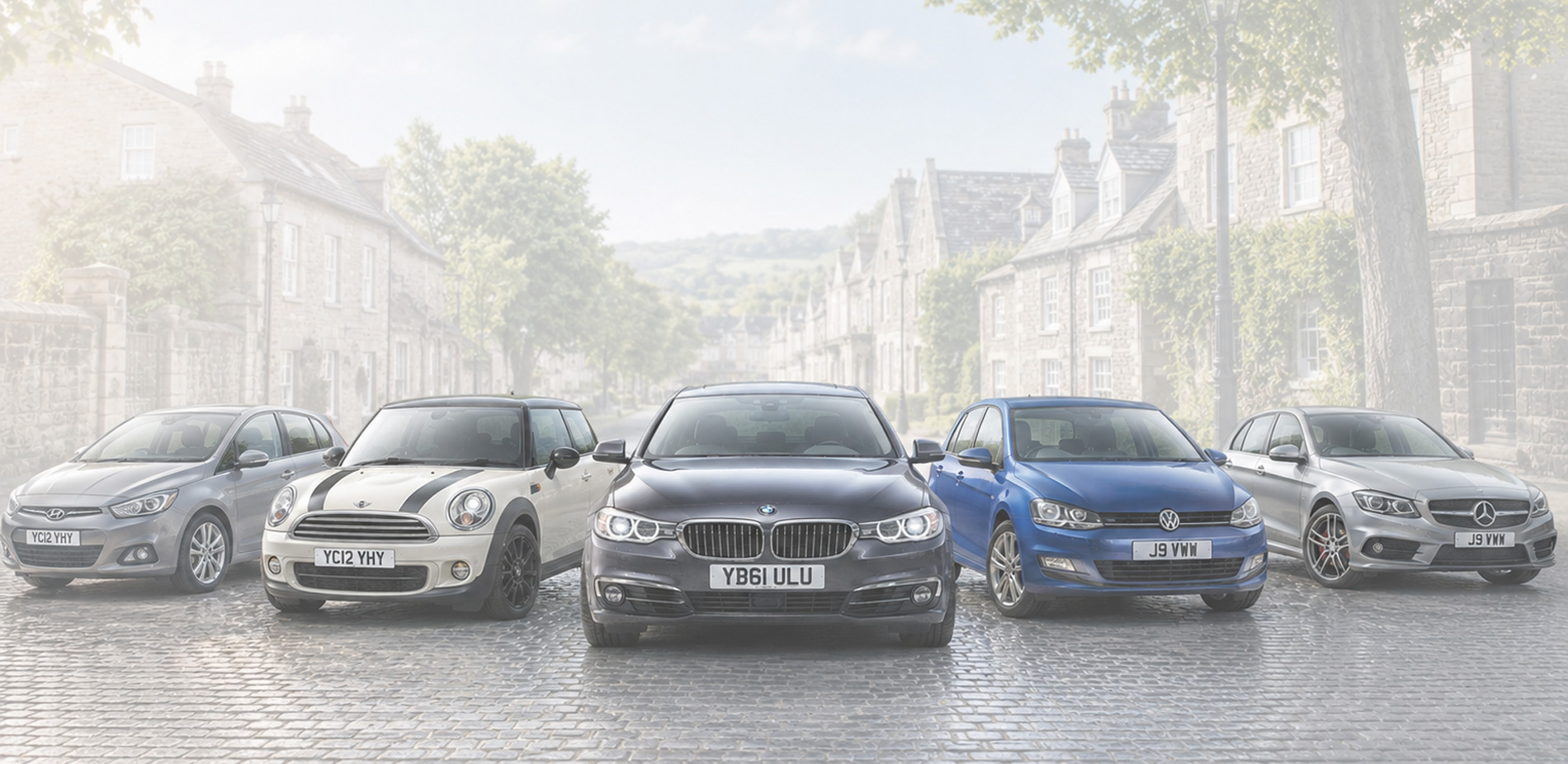 An array of modern cars on a backdrop that could be a small british town